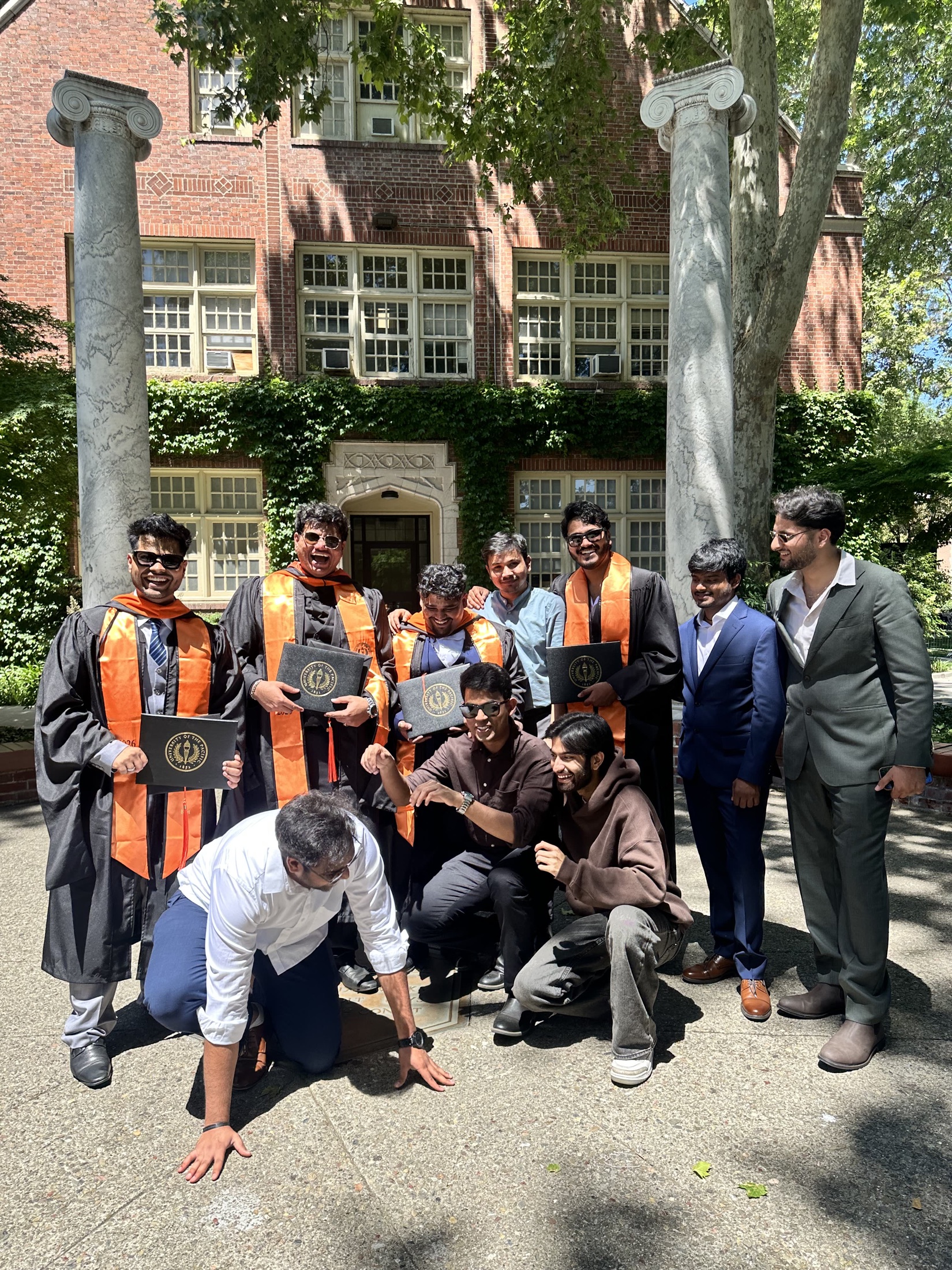 A group of friends celebrating graduation outside a brick building