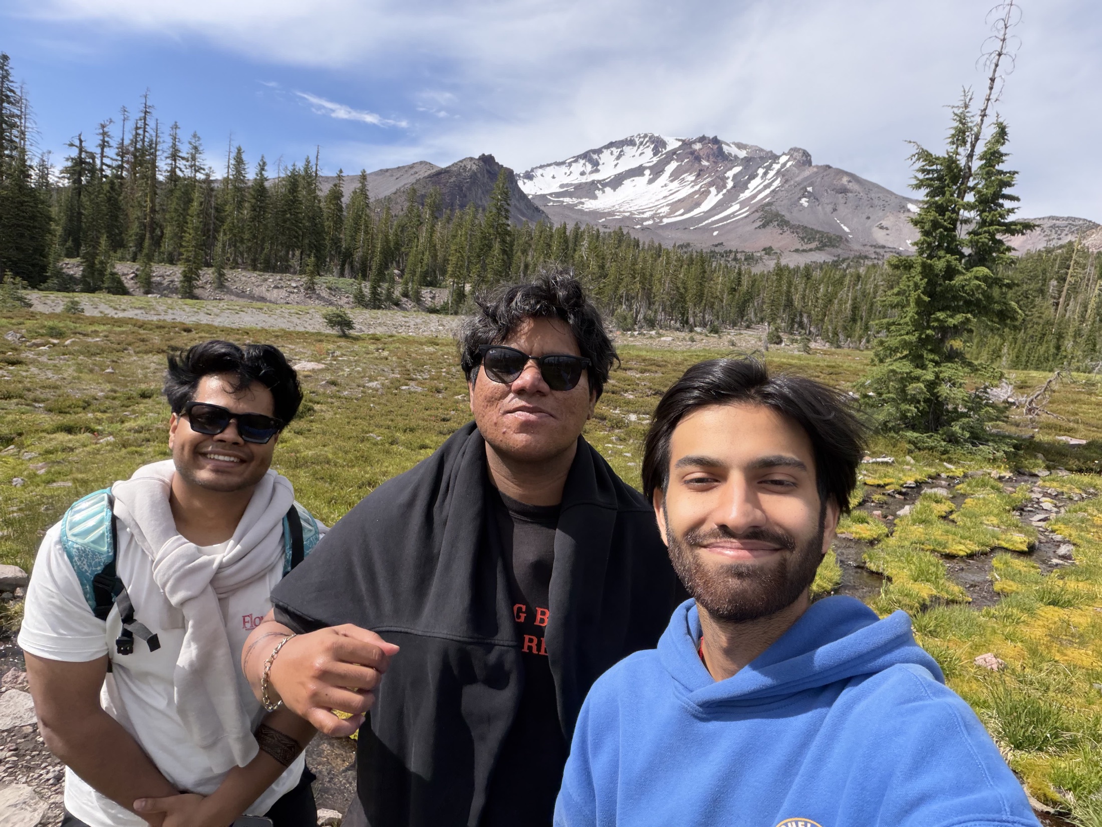 Three friends smiling in front of a mountain landscape
